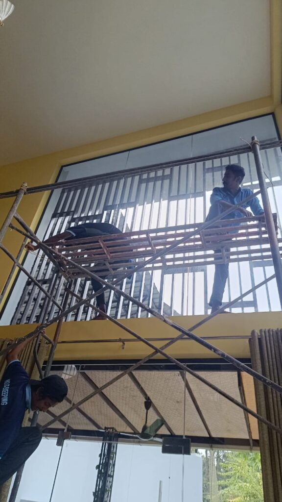 Staff on scaffolding cleaning tall windows and grilles